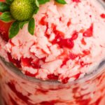 Strawberry butter in a jar shows a light pink color with visible streaks of berry.