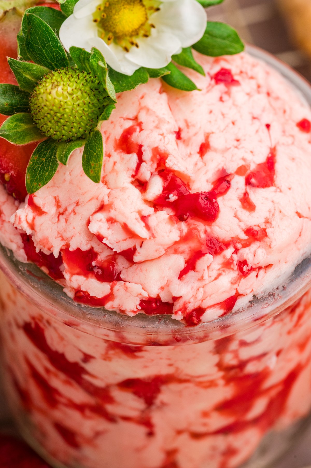 Strawberry butter in a jar shows a light pink color with visible streaks of berry.