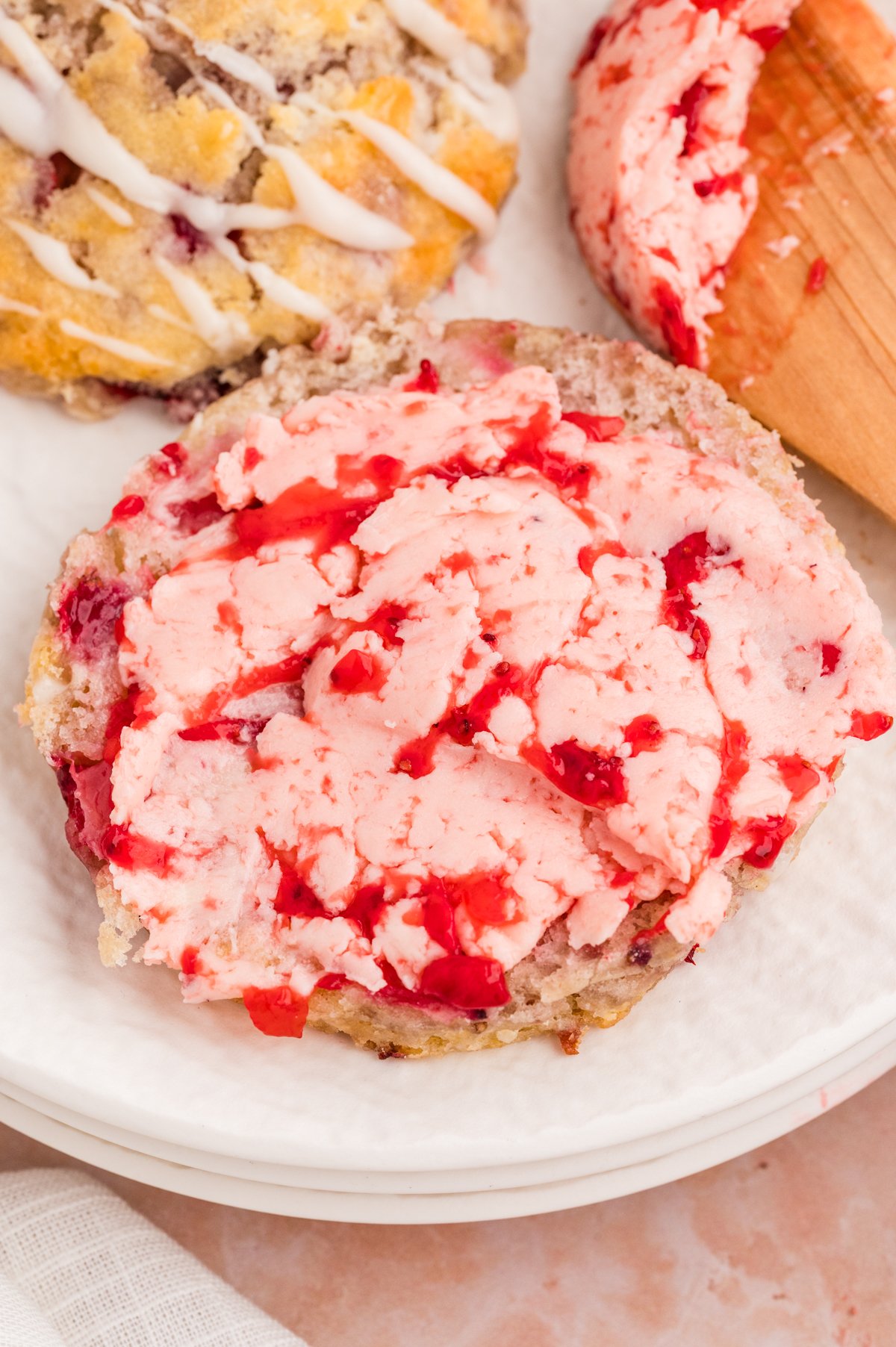 Strawberry butter is spread on a halved biscuit, showing a smooth pink spread with small berry pieces.