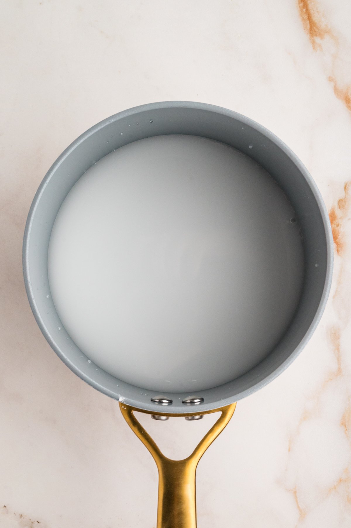 Small saucepan holding a milky white cornstarch-and-water slurry before thickening.