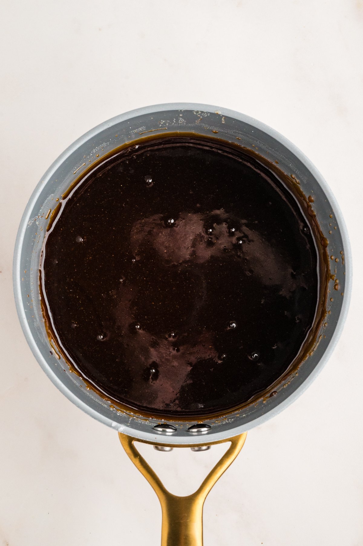 Saucepan filled with glossy, deep brown homemade teriyaki sauce ready for basting.