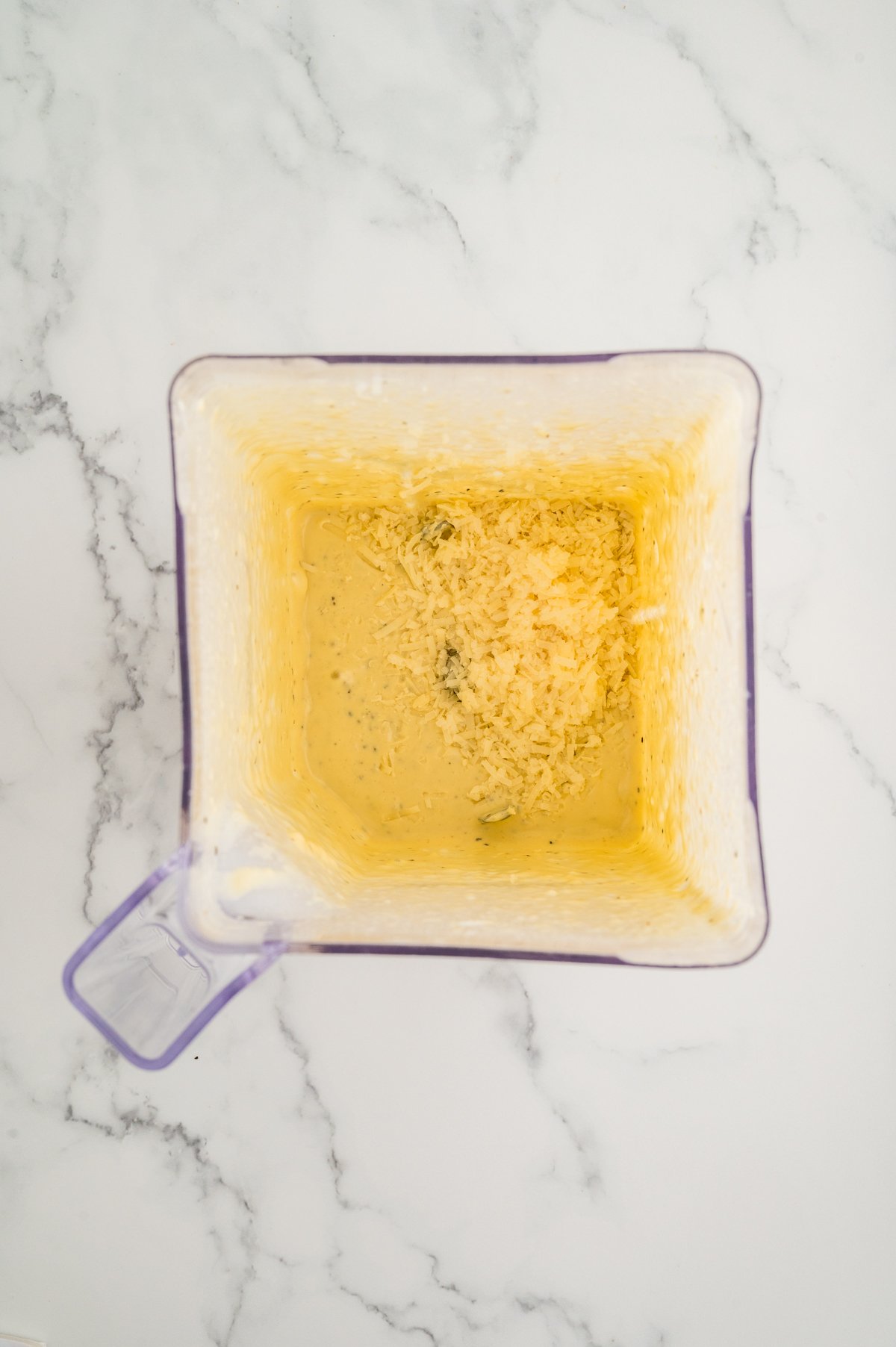 Caesar dressing base after blending with added grated parmesan cheese in a blender container.