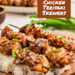 Overhead shot of teriyaki chicken skewers on a bed of rice, garnished with sesame seeds and green onions, with a brown square overlay in the top right that reads ‘acupofcream.com Chicken Teriyaki Skewers'.