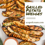 Vertical graphic showing a white cutting board topped with a heap of grilled potato wedges sprinkled with chopped herbs. In the top right corner is a round wooden bowl of pink sauce. A white rectangular text overlay on the right reads “Grilled Potato Wedges” in bold script, with “acupofcream.com” below